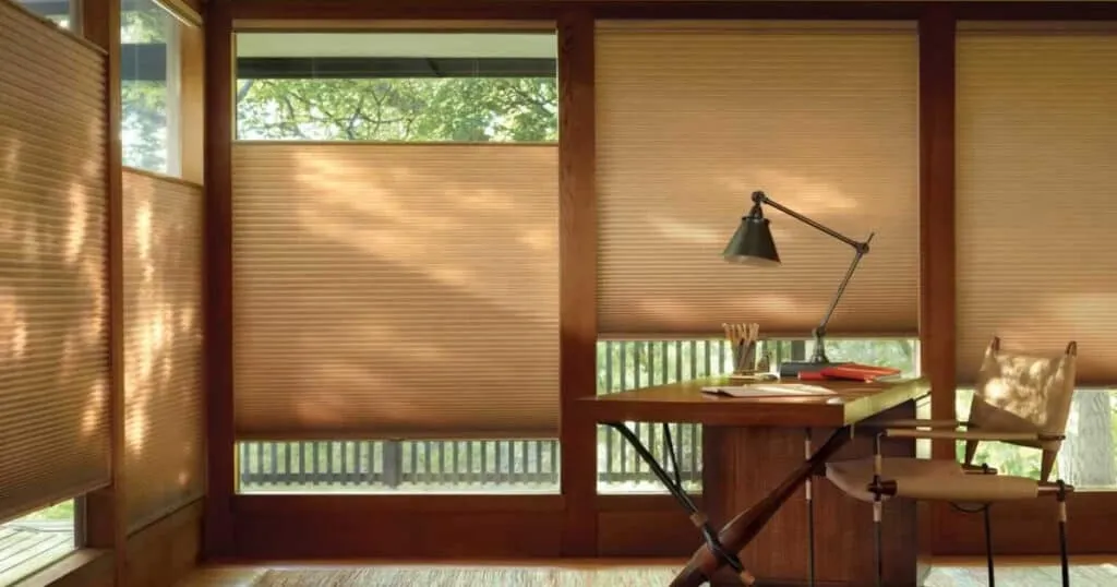 Soft beige window blinds in a home office with natural sunlight, creating a warm, cozy atmosphere ideal for comfort and privacy. Perfect for enhancing interior decor with quality window treatment.