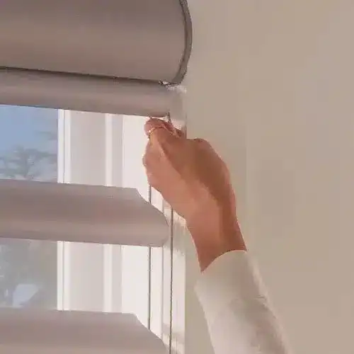 White window blinds being adjusted with a hand, showcasing easy operation and sleek design. Perfect for enhancing home aesthetics and controlling natural light.