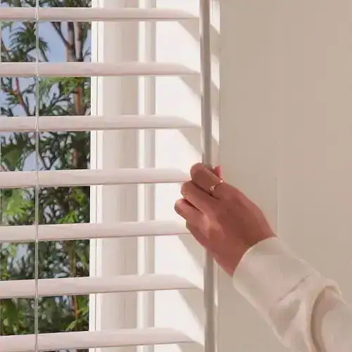 Adjustable white plantation blinds on a window, controlling natural light and privacy, ideal for stylish home décor.