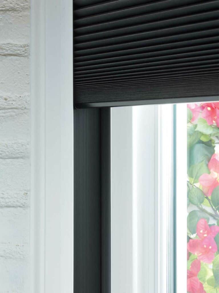 Black horizontal window blinds on a white window frame, showcasing modern design and privacy features.