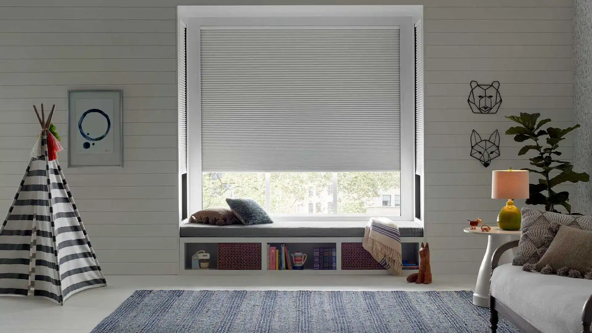 Modern interior window with white roller blinds offering light control and privacy, complemented by cozy decor.