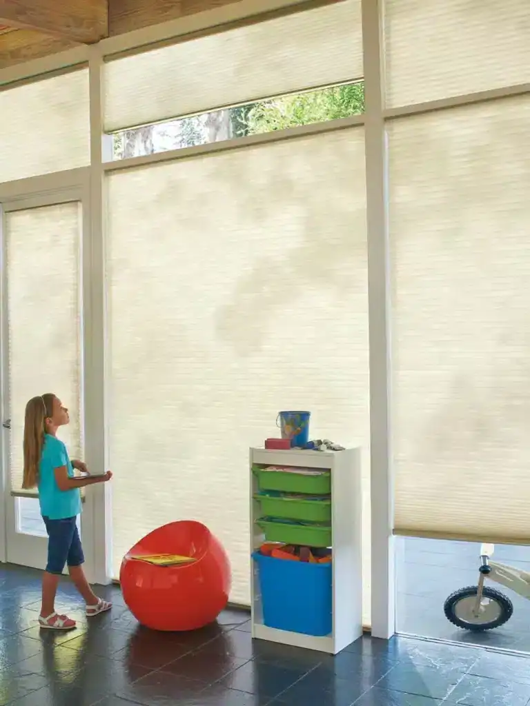Light filtering beige window blinds providing privacy and sun control in a bright indoor space with children and playful decor.