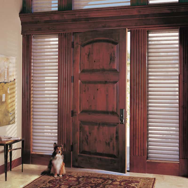 Wooden front door with matching window shutters and blinds, showcasing custom window treatment options by Superior Blinds. Perfect for enhancing curb appeal and controlling light in your home.