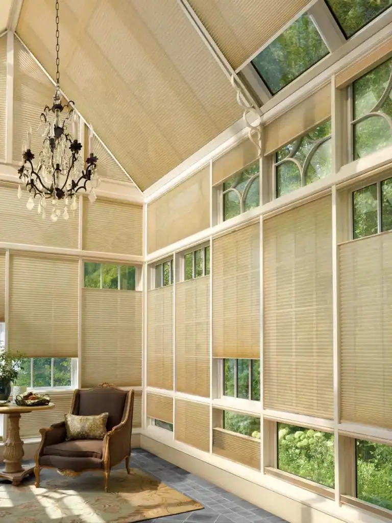 Elegant beige window blinds for sun protection and privacy in a bright sunroom with a vintage armchair and chandelier.