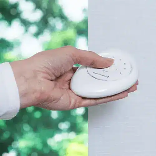 Remote control for smart home window blinds, universal remote, wireless home automation device, or light switch control in living room.