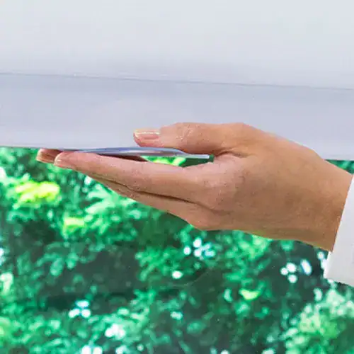 Adjustable white blinds with a close-up of a person's hand interacting with the window treatment, showcasing quality window covering options from Superior Blinds.