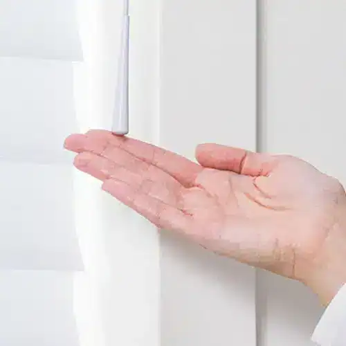 Smooth white window blinds controlled by a hand, showcasing accessible window treatment options.