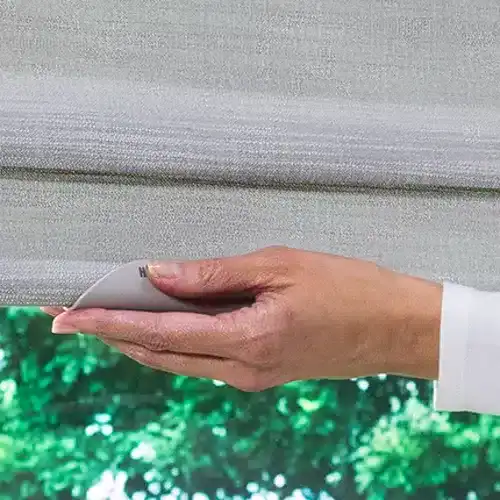Adjustable fabric roller shade being operated with a remote control on a window.