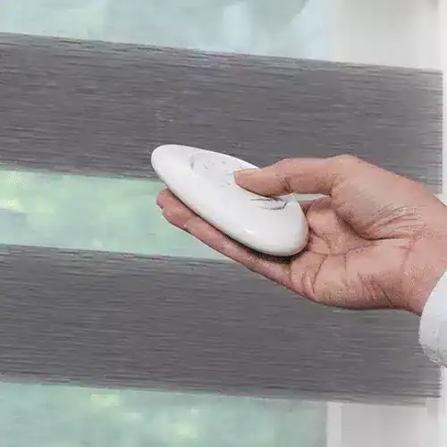Smooth gray roller blinds being cleaned with a white cloth, showcasing high-quality custom window treatment options.