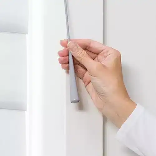 Smooth white window blinds being adjusted with a rod, showcasing quality and modern design.