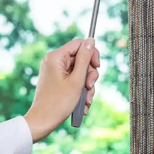 Adjustable window blind being operated with a hand-held wand for light control and privacy.